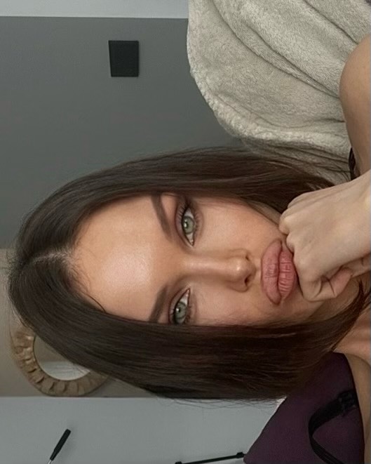 Woman with long dark hair resting her chin on her hand and looking at the camera.