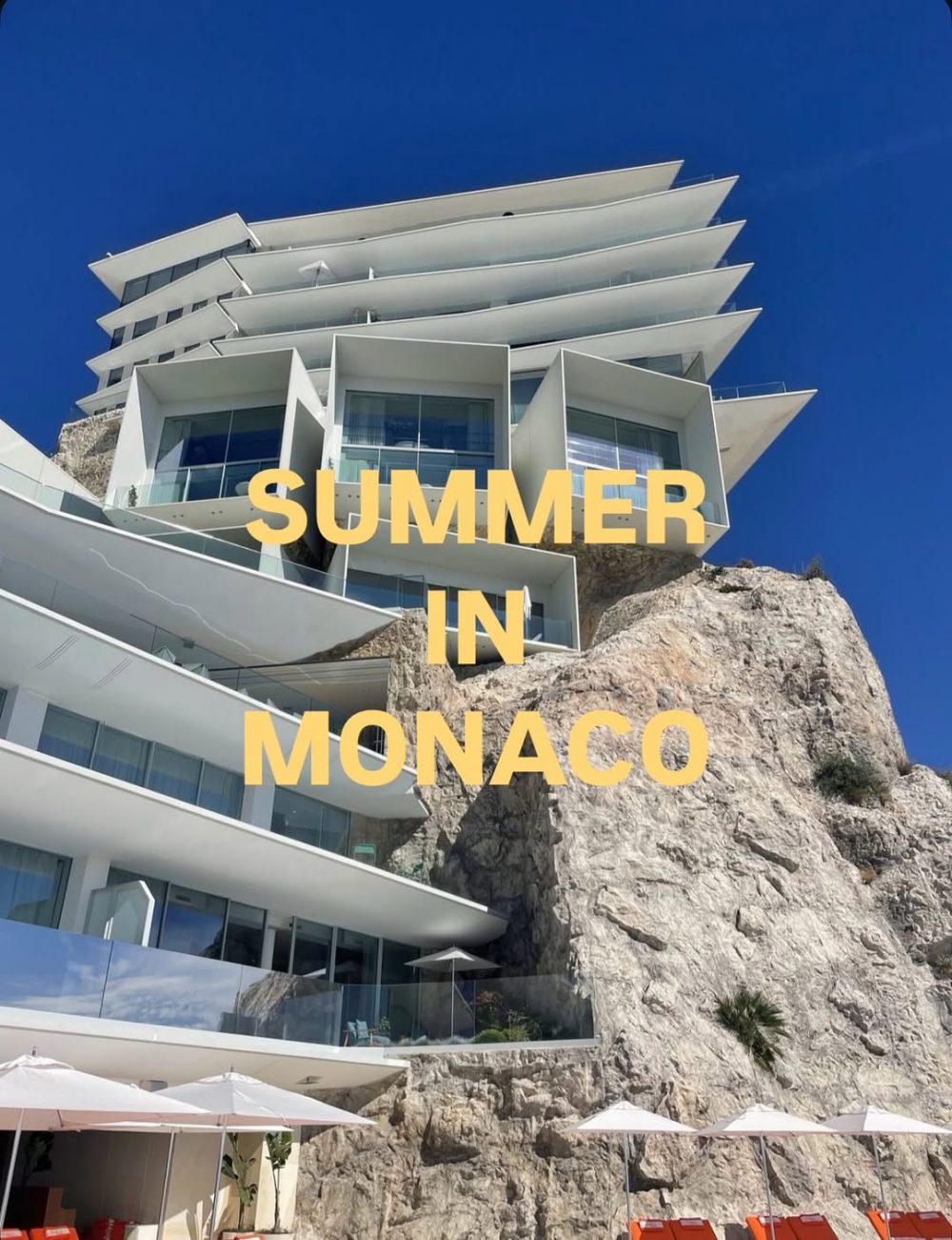 White cliffside hotel with stacked terraces, blue sky, and yellow text: SUMMER IN MONACO.