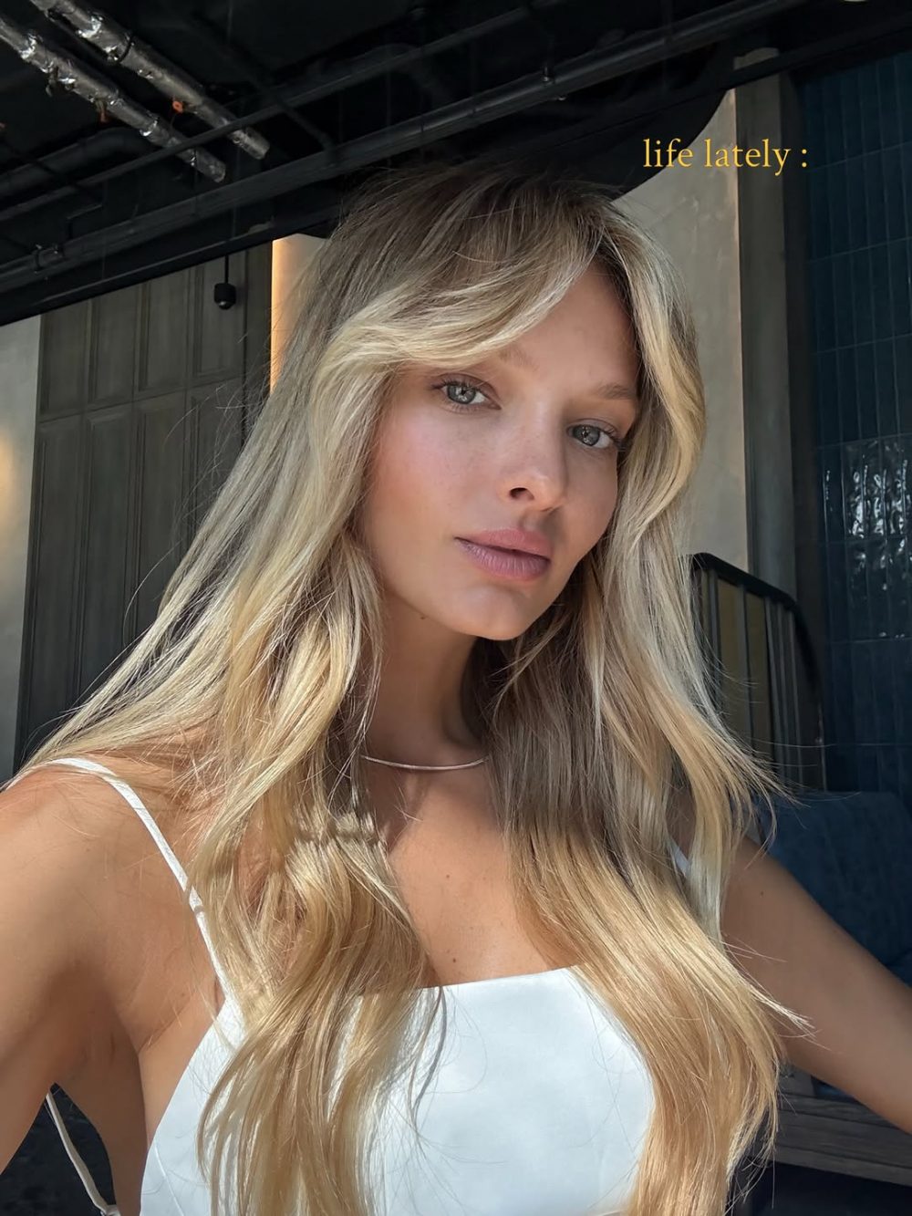 Portrait of a blonde woman in a white spaghetti-strap top with a silver necklace, looking at the camera; caption 'life lately:' in the corner.