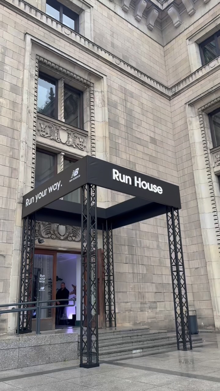Entrance to a Run House event sponsored by New Balance, under a black canopy on a stone building façade.