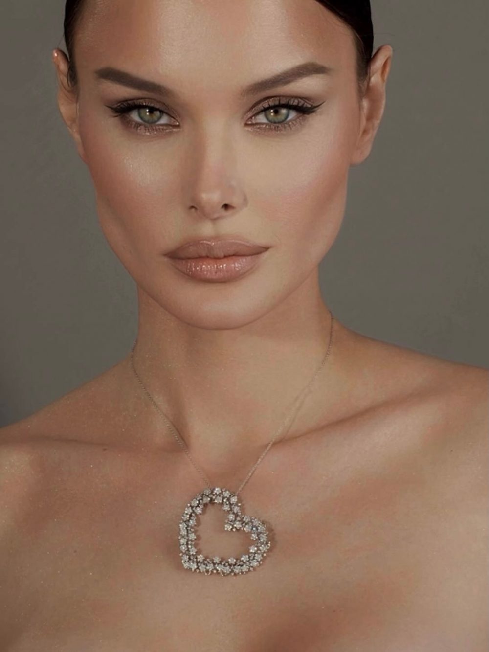 Close-up of a woman with a diamond heart pendant necklace resting on her collarbone