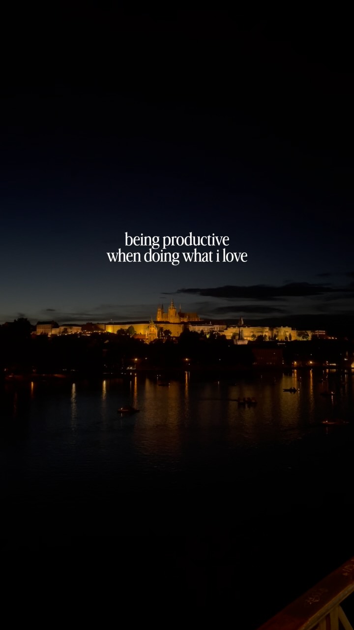 Night cityscape along a river at dusk with warm-lit buildings; white text overlay reads 'being productive when doing what i love'.