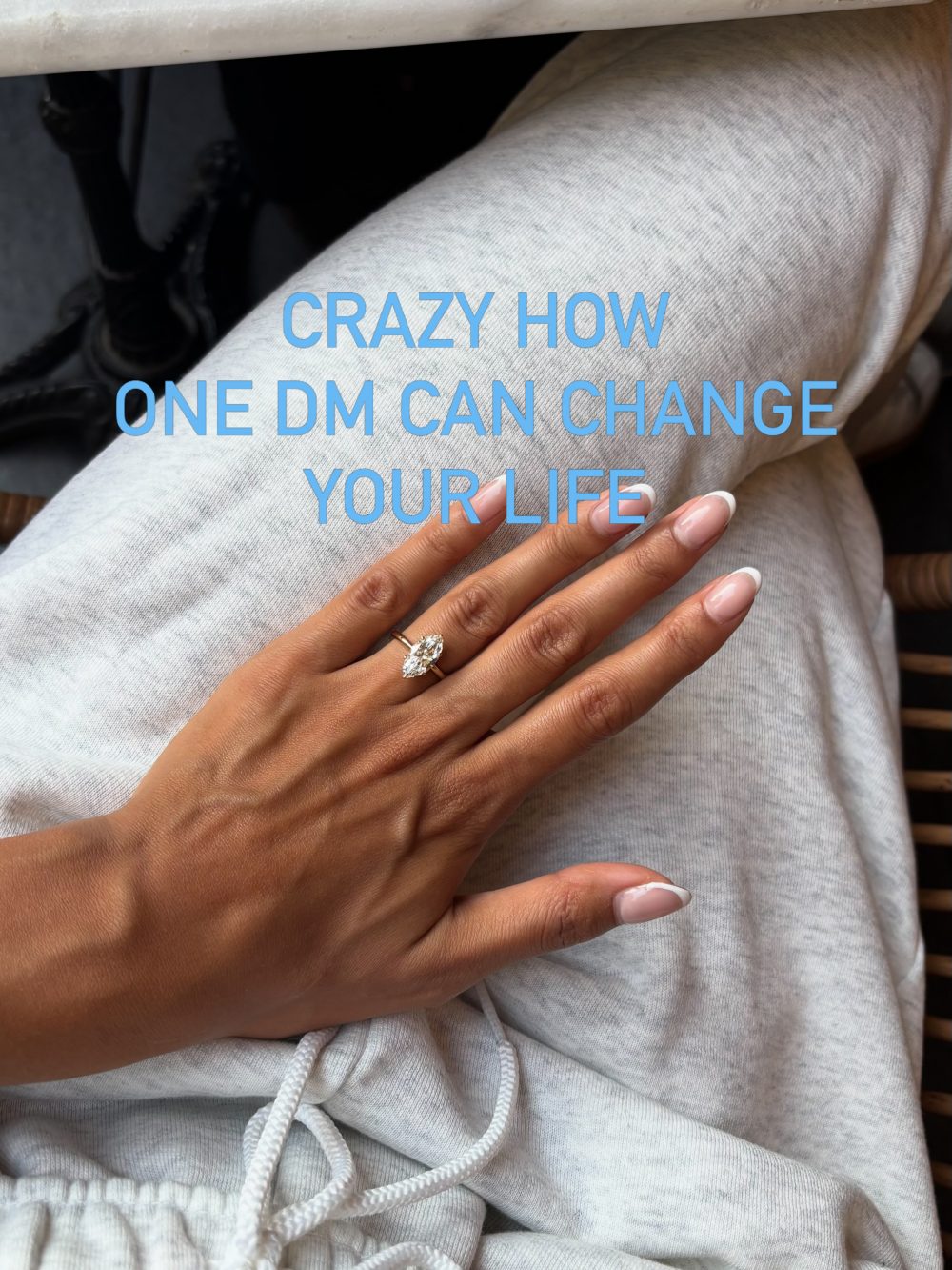 Hand with a diamond ring resting on gray fabric with blue text saying, 'CRAZY HOW ONE DM CAN CHANGE YOUR LIFE'.
