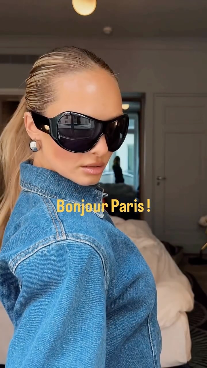Woman wearing oversized black sunglasses and a denim jacket, looking over her shoulder with the caption 'Bonjour Paris!'