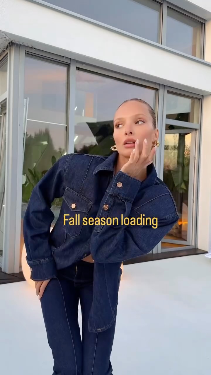 Person in a dark denim jean jacket and jeans posing outdoors with hand on face, caption reads 'Fall season loading' in yellow text.